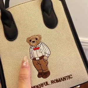 แหล่งที่มาของ Beibaobao 2024 กระเป๋าผู้หญิงรุ่นใหม่ฤดูร้อนกระเป๋าถือลายปักลายหมีกระเป๋าสะพายข้าง