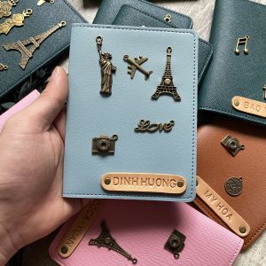 Bọc hộ chiếu màu xanh lam nhạt khắc tên theo yêu cầu charm decor đậm chất retro. Ghép charm thành tên chủ nhân độc đáo