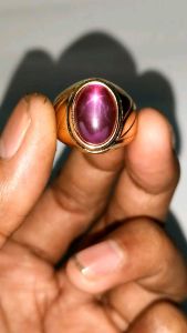 Cincin MERAH SIAM ROSE STAR BANGKOK dengan batu permata merah muda berkilauan di tengah bingkai emas mengkilap cocok untuk acara formal.