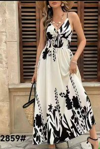 White floral maxi dress with black patterns. Sleeveless design. Elastic waist. Long flowing skirt. Casual summer outfit. Outdoor setting.