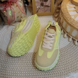 Beige and yellow sneakers with white laces and textured soles. Casual footwear for everyday wear.