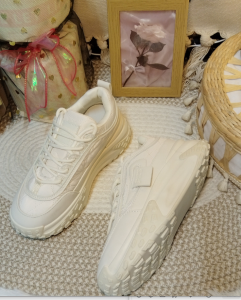 White sneakers with thick soles and textured design. Casual footwear