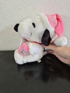 Snoopy with a pink hat & pink gloves holding a letter with a ribbon & a paw print
