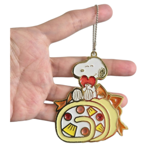 Snoopy on top of a Swiss roll cake hanging enamel decoration