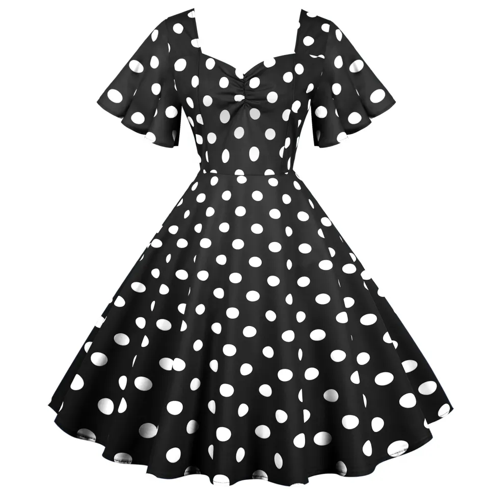 Young women wearing vintage polka dot dresses dancing in city park